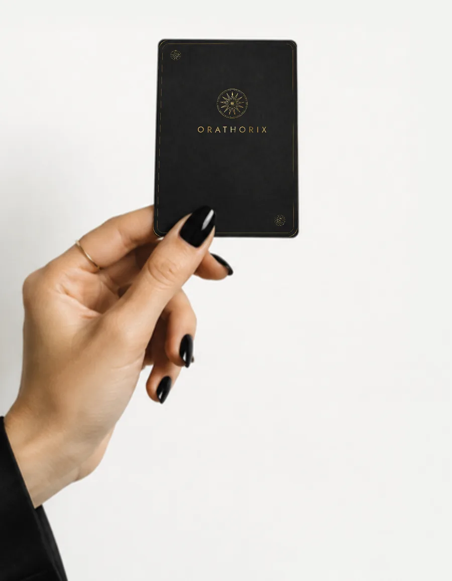 Una mano enseña una carta Orathorix negra con el logo en oro