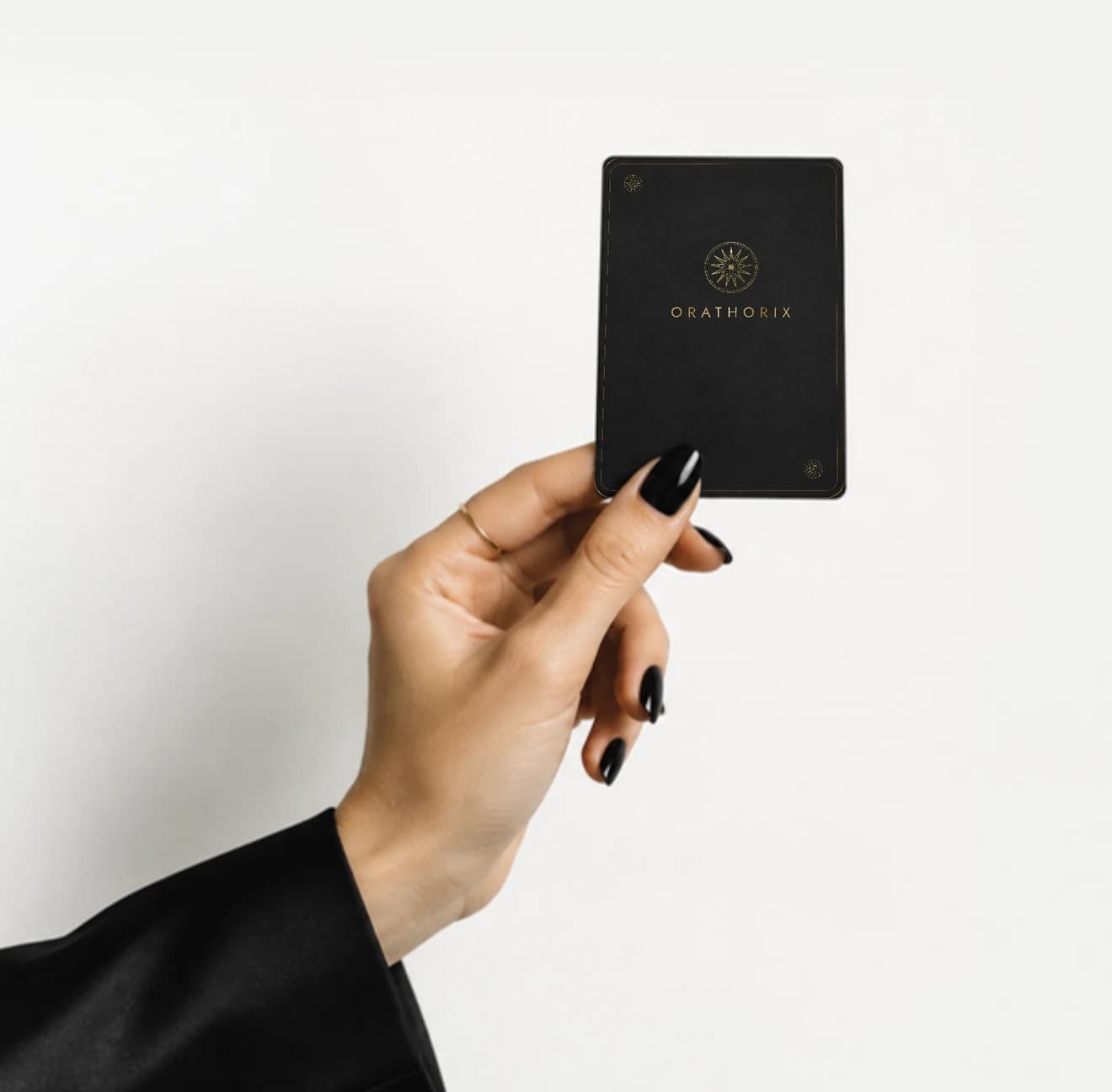 Una mano enseña una carta Orathorix negra con el logo en oro
